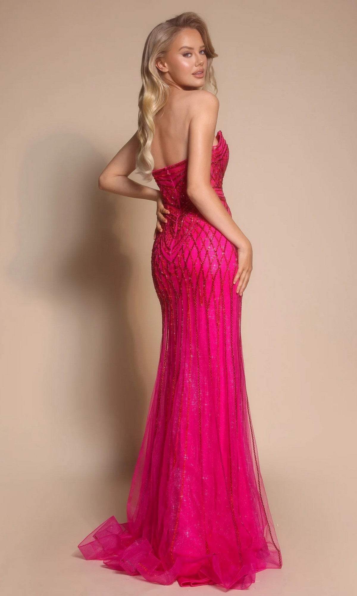 Woman wearing the Portia and Scarlett PS26072 long formal dress with rhinestone embellishments and a thigh-high slit, posing with one hand on her hip against a plain beige background.
